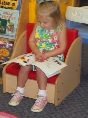 Child sitting in a chair reading a book