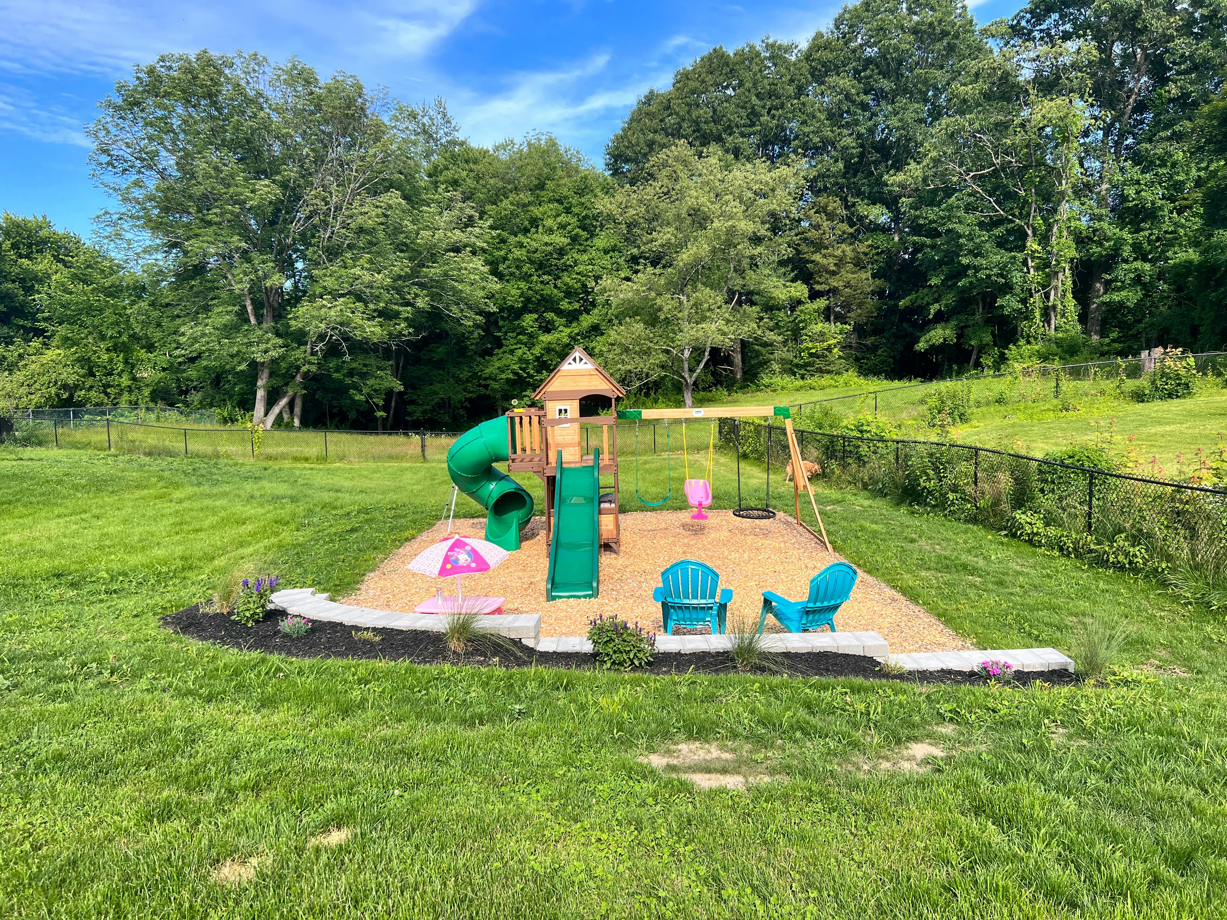 Outdoor playground with slides, swings, and a small playhouse