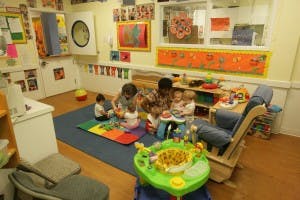 Adult and three children playing with toys on a mat in a room