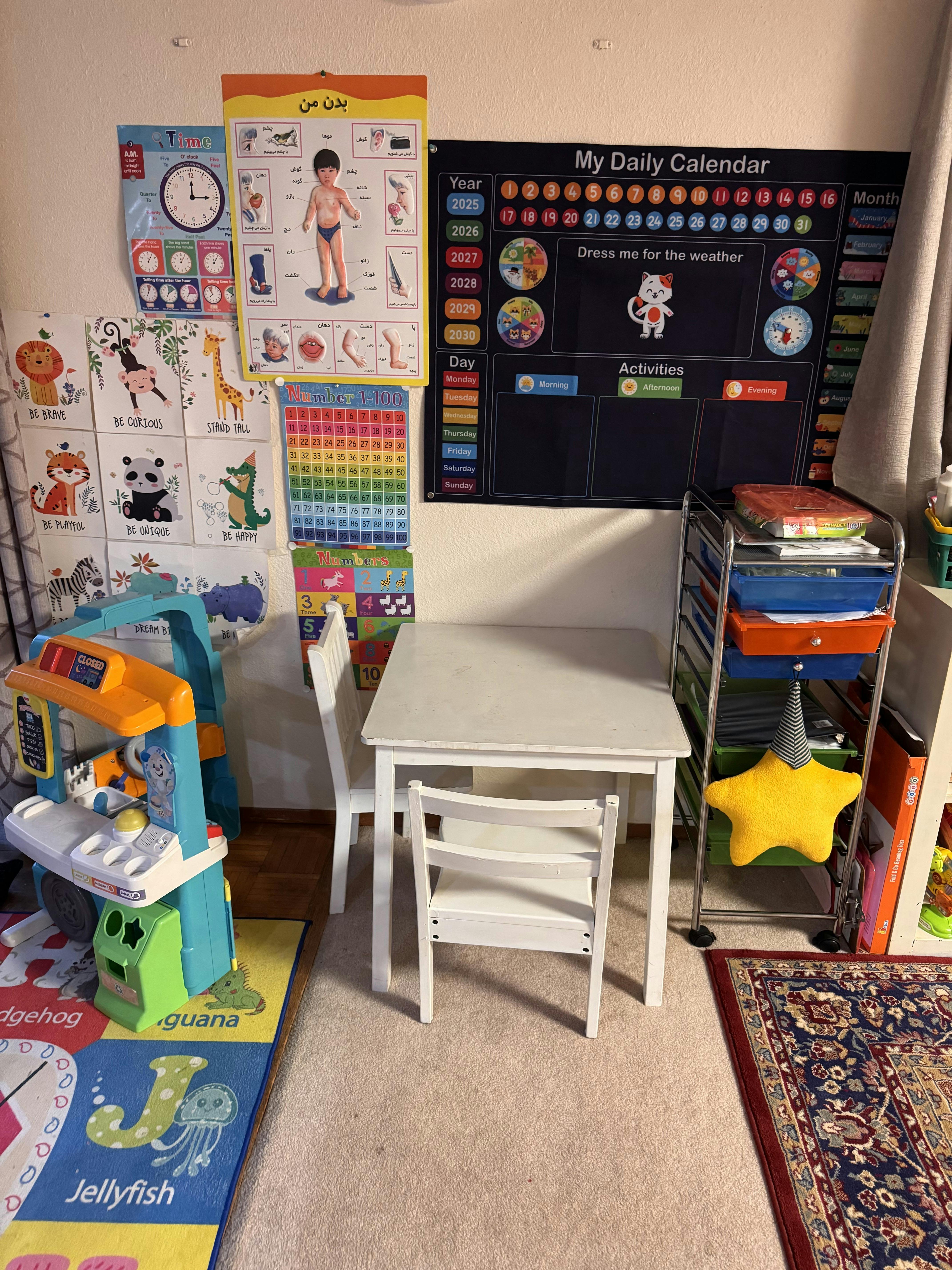 Children's white table and chairs in a playroom with educational wall charts