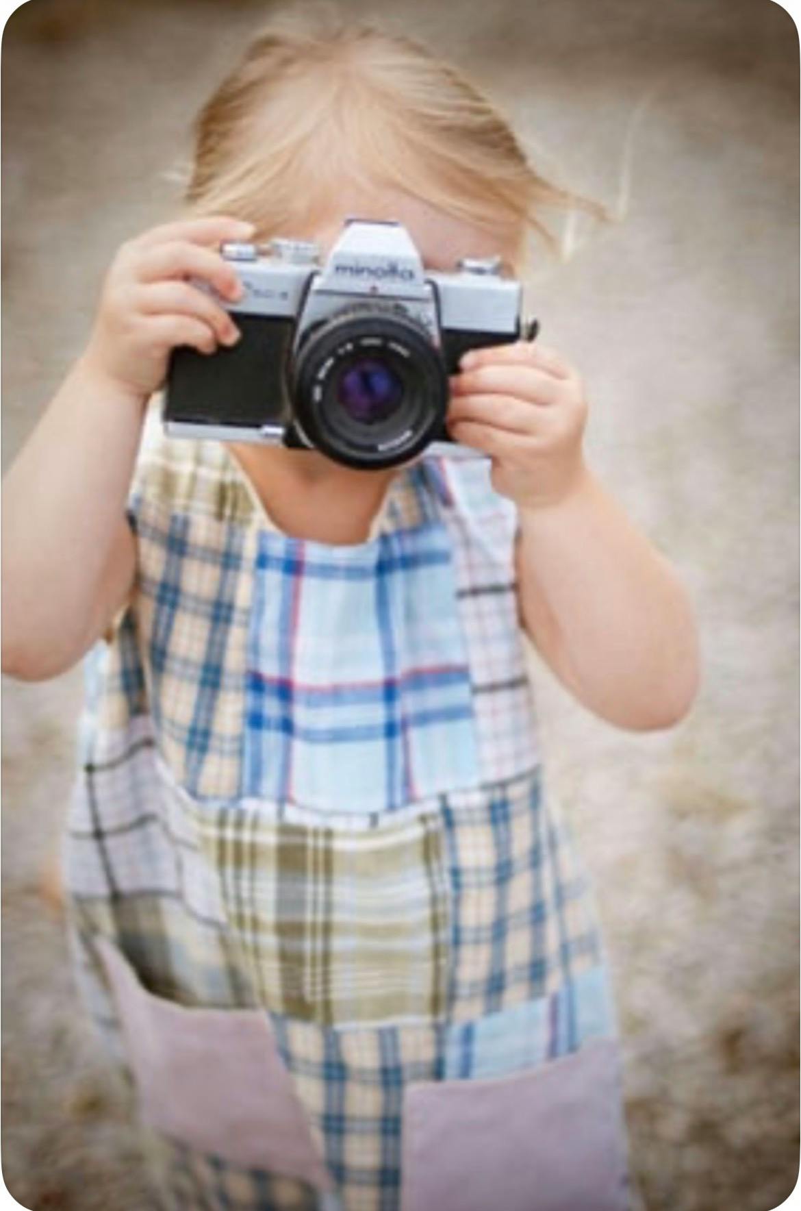 Child holding an old film camera up to their face