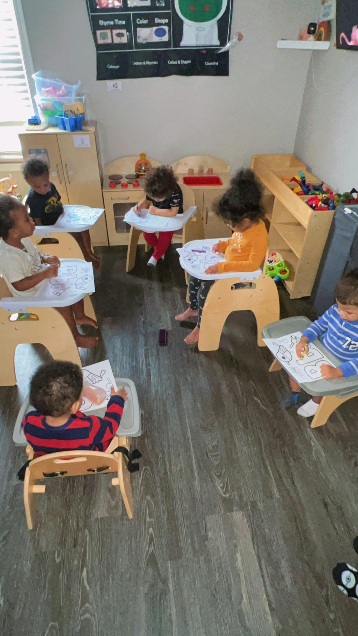 Children sitting at small tables coloring in a classroom