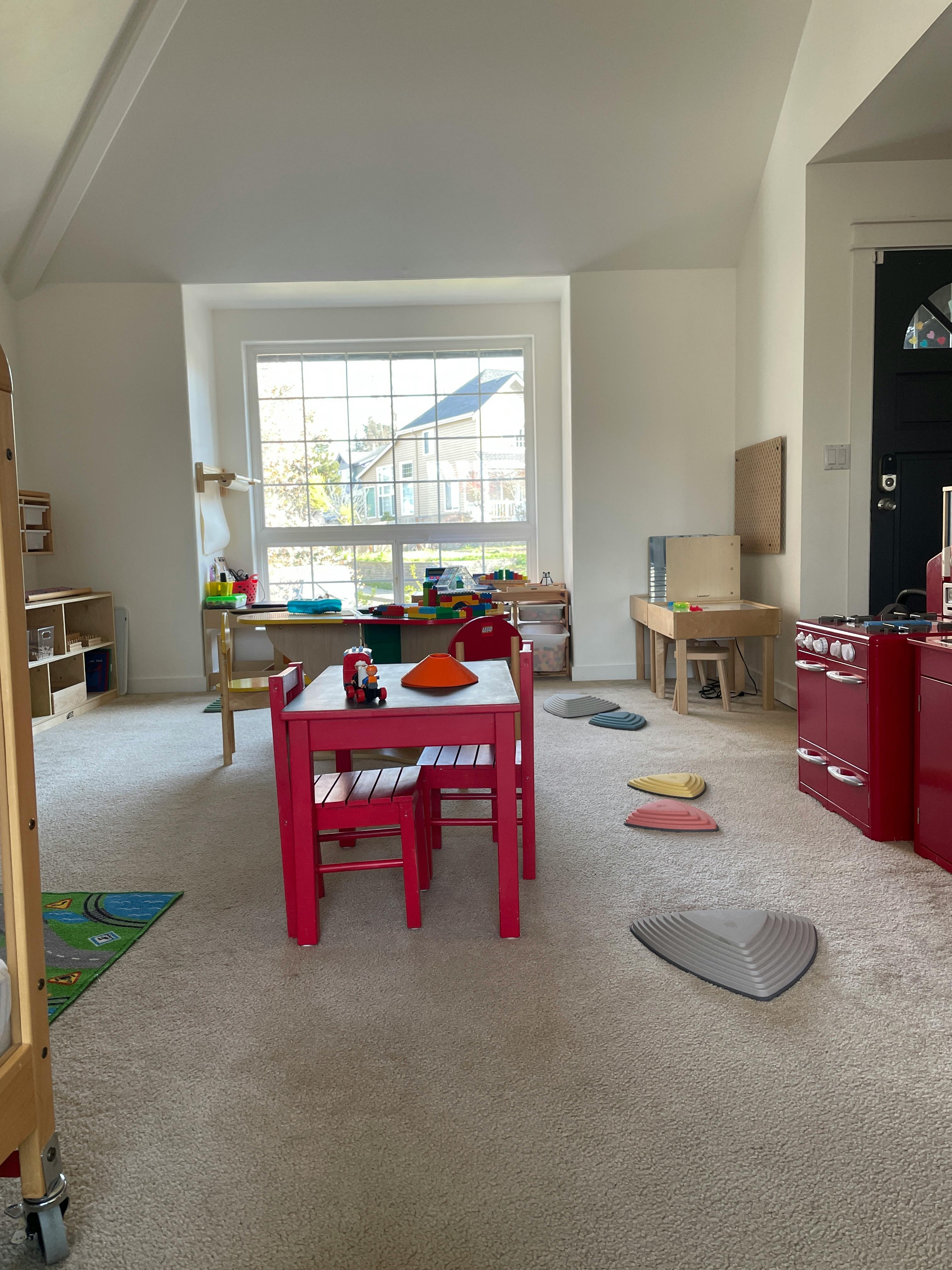 Playroom with red table and chairs, toy kitchen, and window