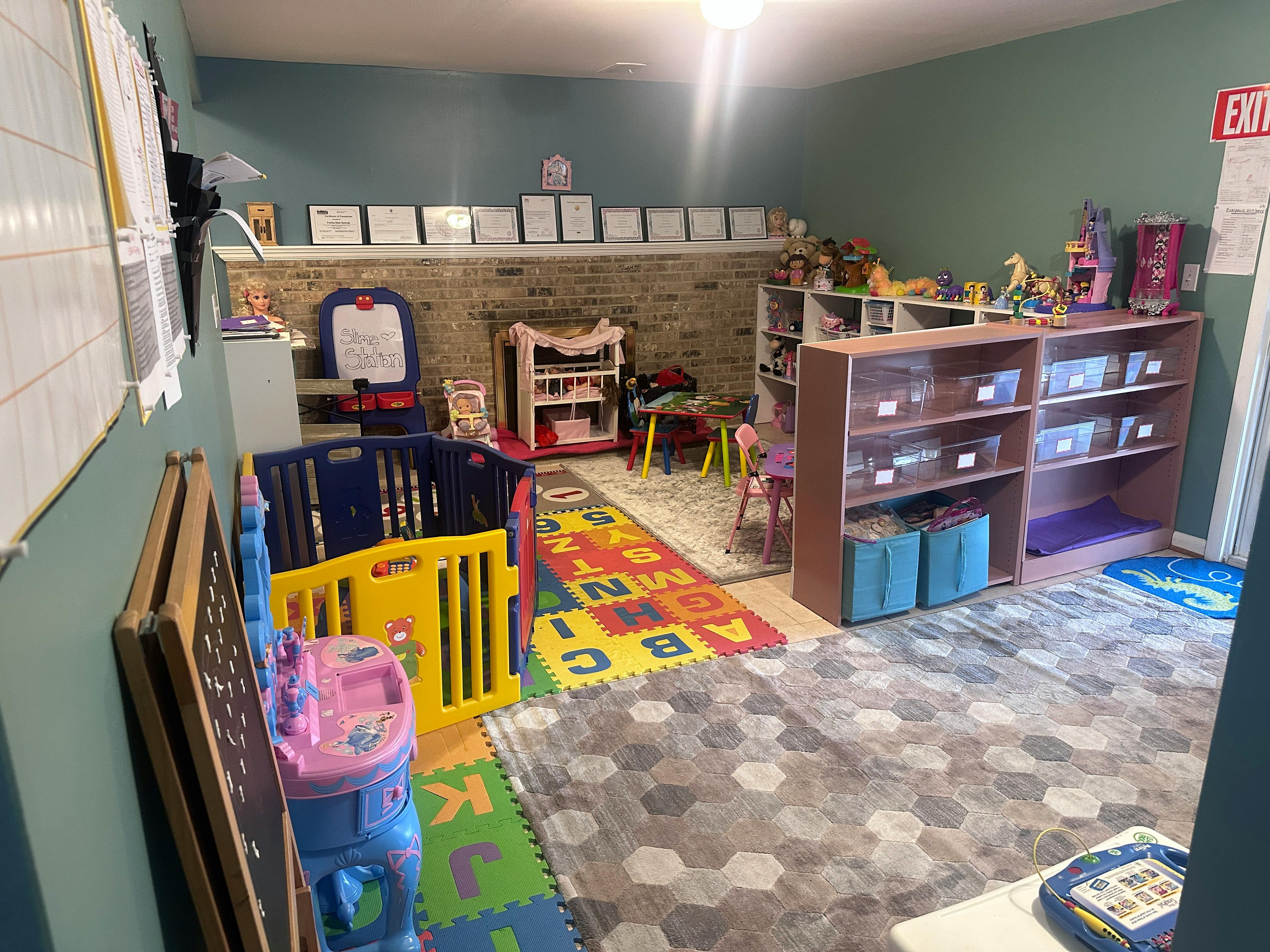 Playroom with colorful mats, playpen, and shelves of shelves with toys