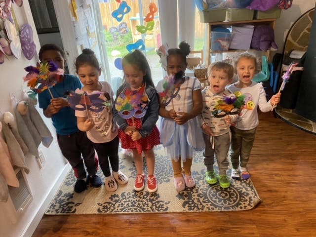 Six children holding colorful masks and wands