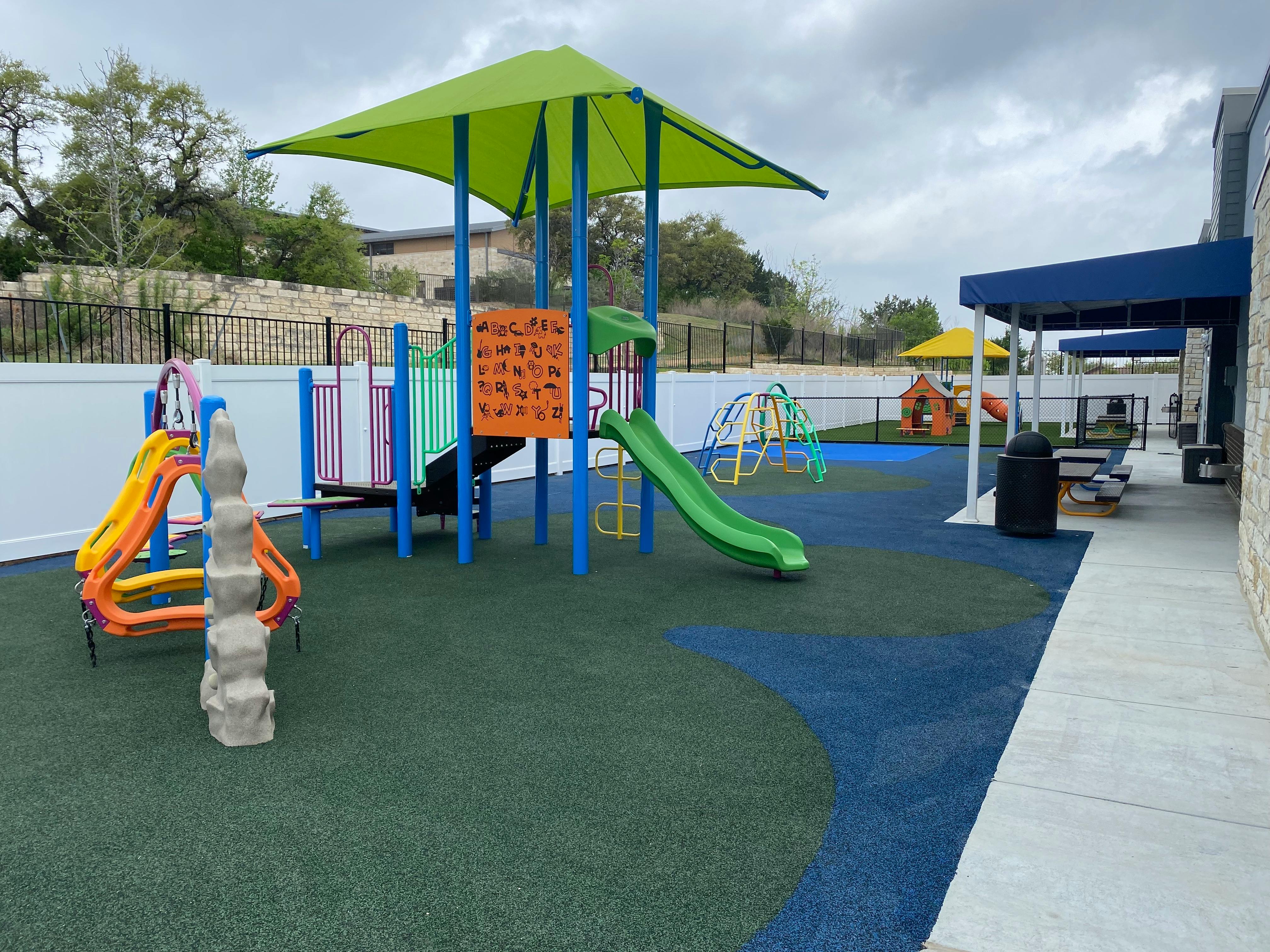 Outdoor playground with slides, climbing structures, and green and blue ground