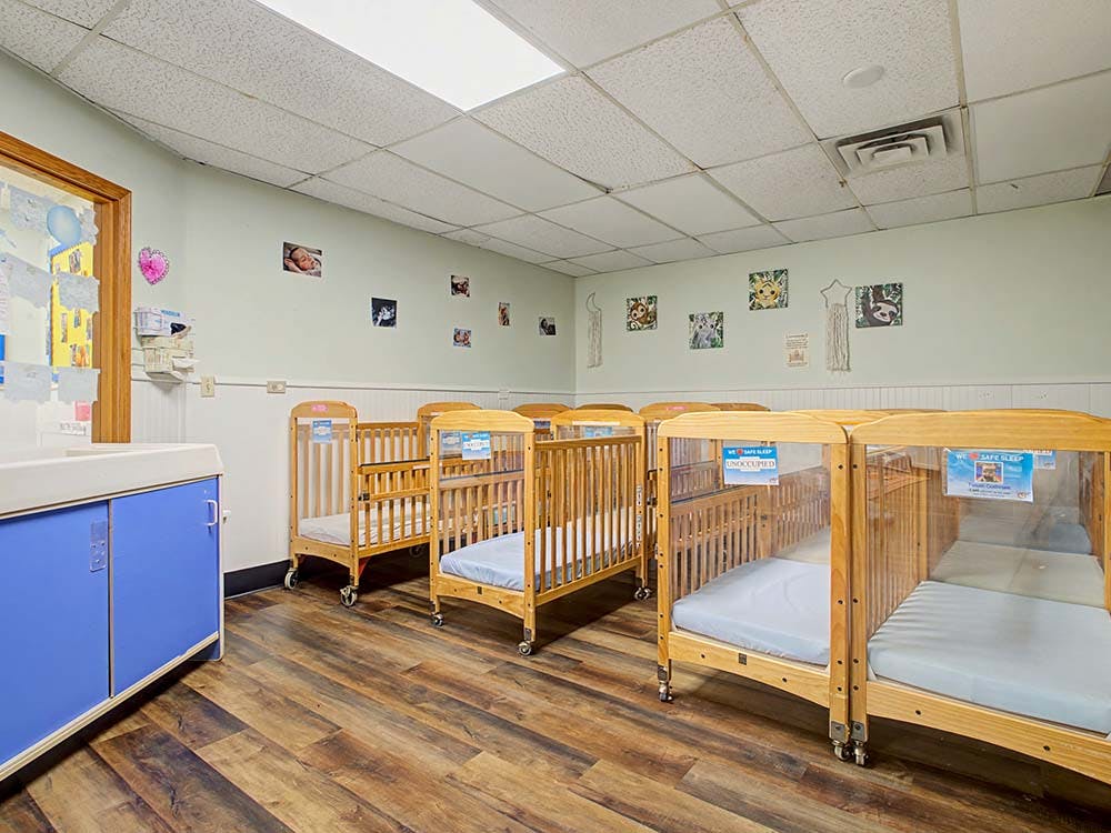 Cribs with clear side panels in a nursery or daycare room