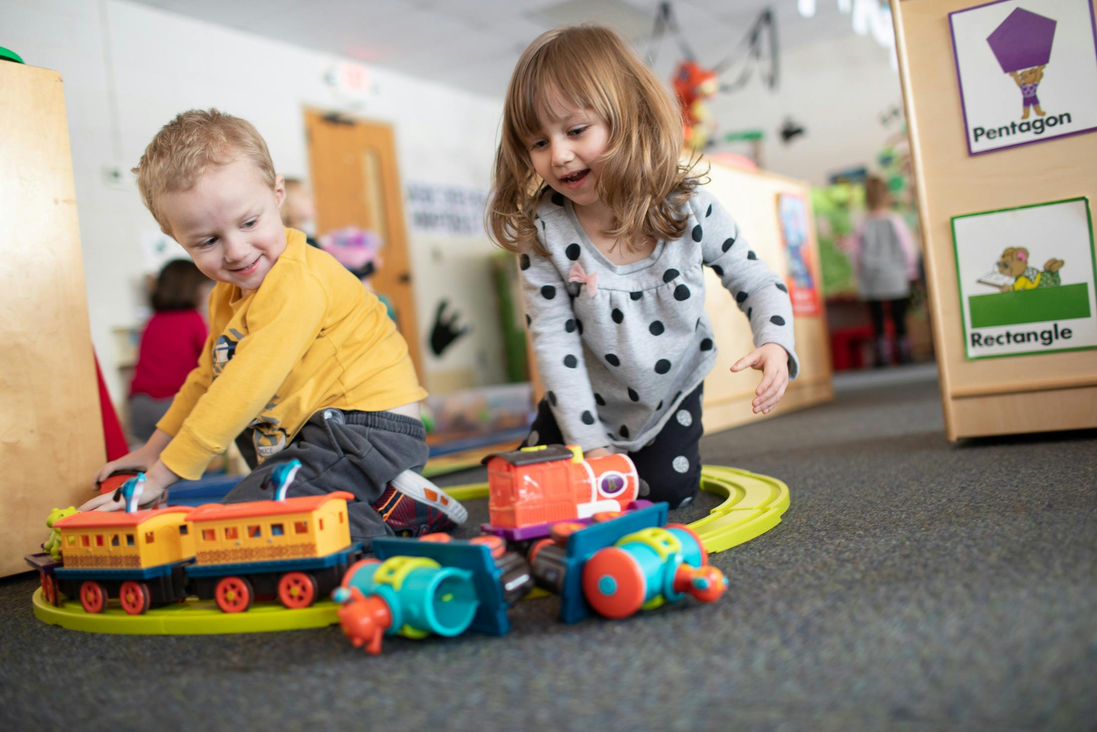 Two children playing with toy trains on the floor