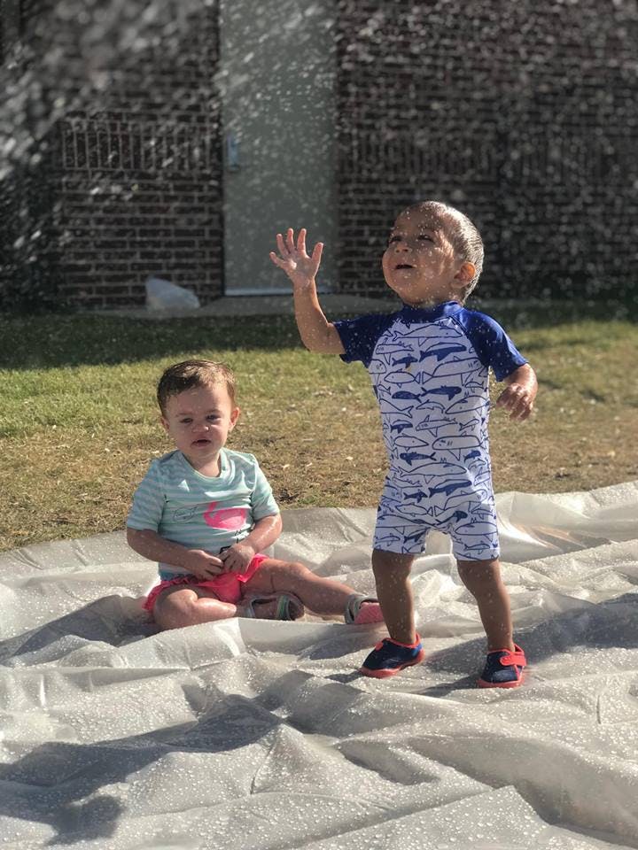 Two children playing on a white sheet with water