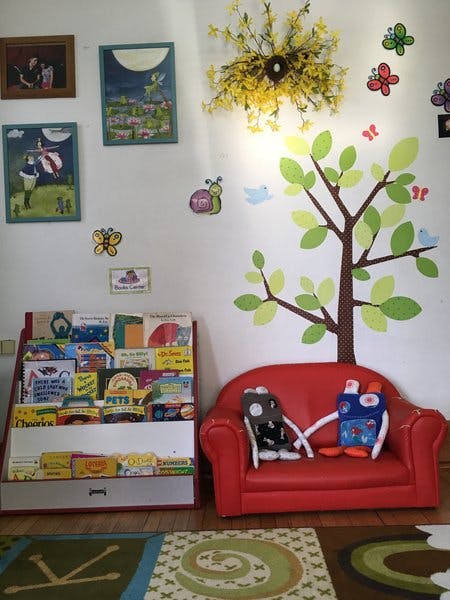 Children's reading nook with a red couch and a bookshelf filled bookshelf