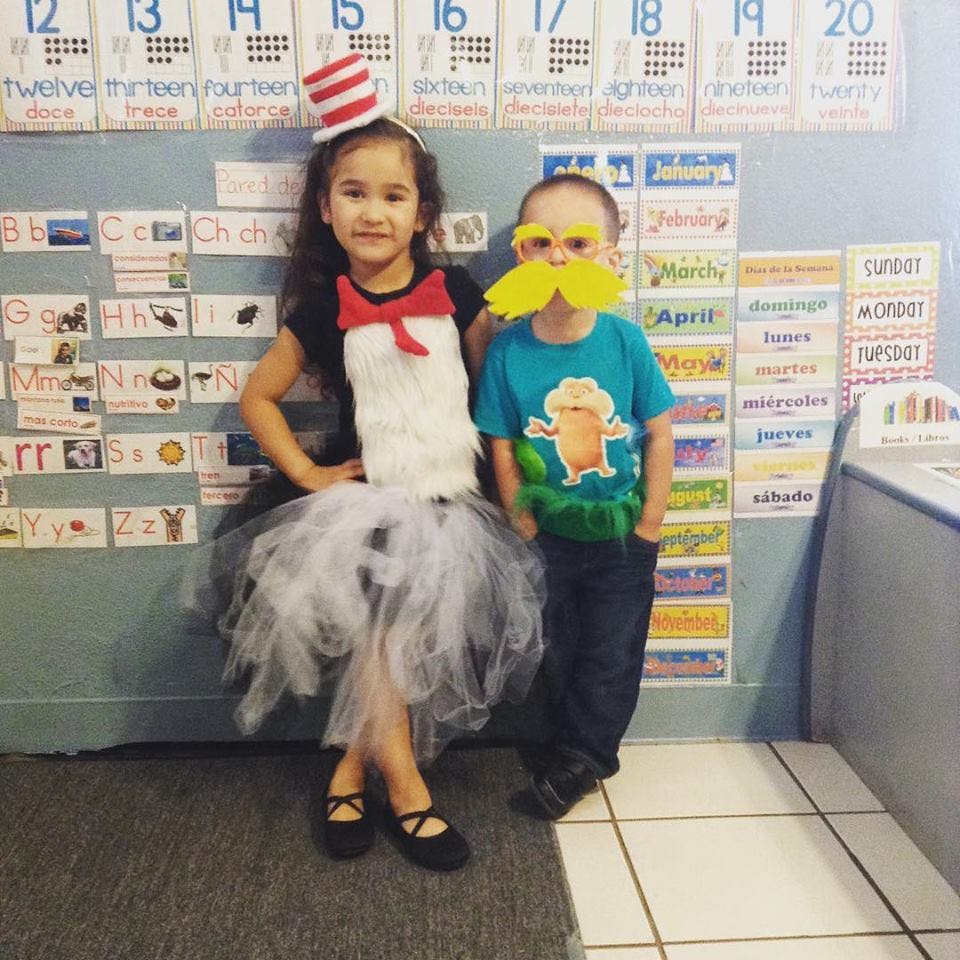 Two children in costumes standing in a classroom