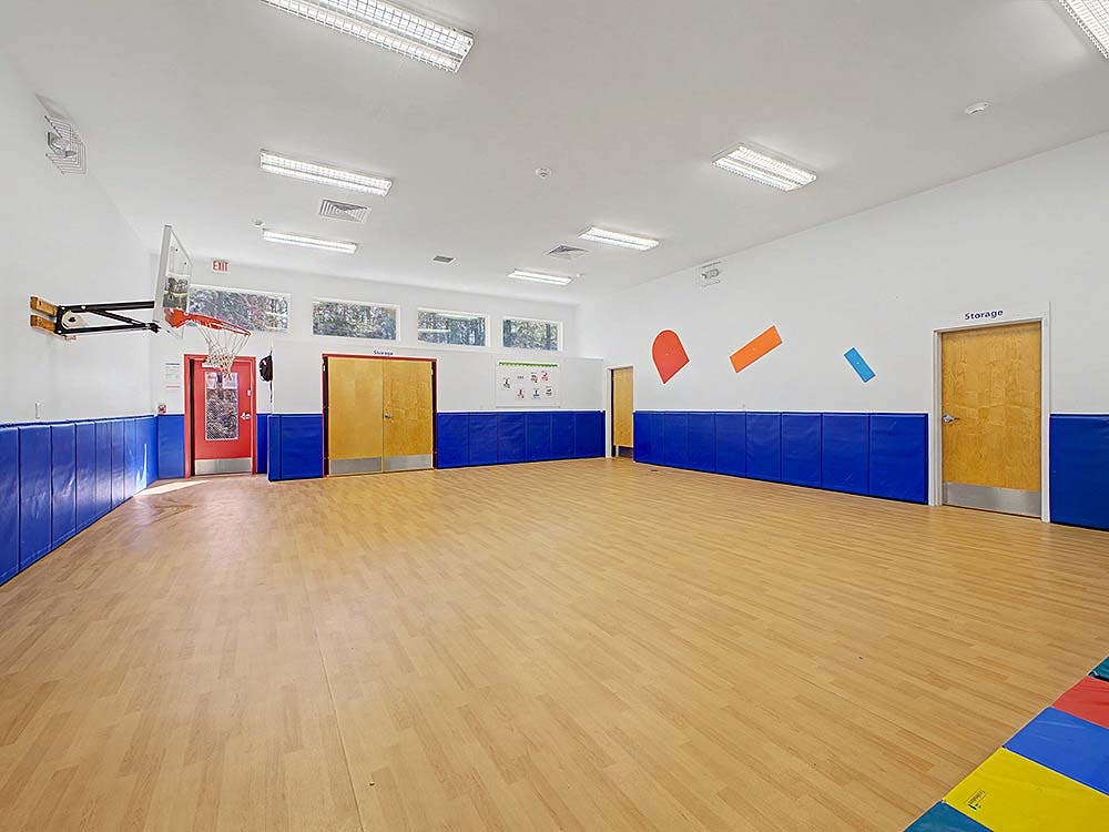 Basketball hoop in a brightly lit gym with padded blue walls
