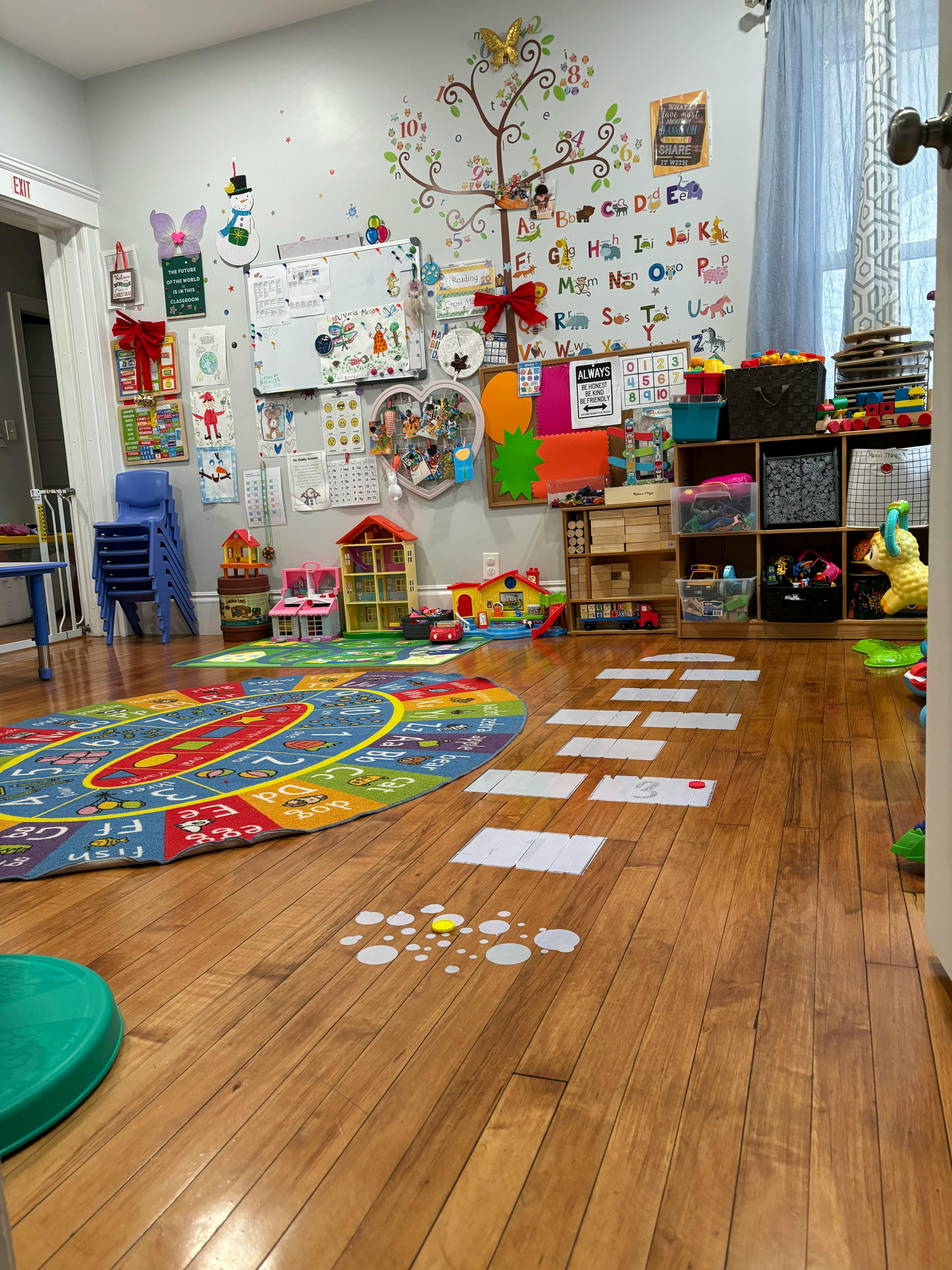 A classroom with a colorful rug, toys, and decorations on the wall