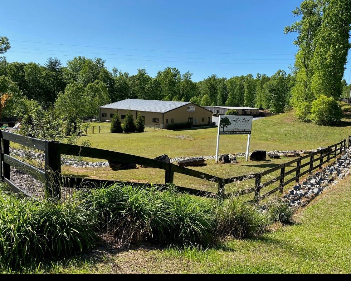 Building with a gray roof behind a wooden fence and green grass