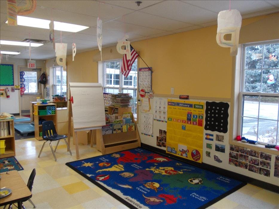 Classroom with a world map rug, whiteboard easel, and calendar wall display