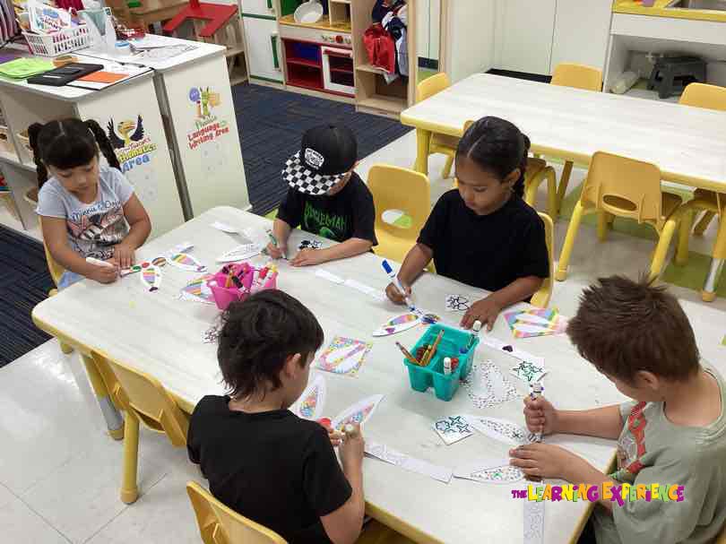 Four children coloring at a table in a classroom
