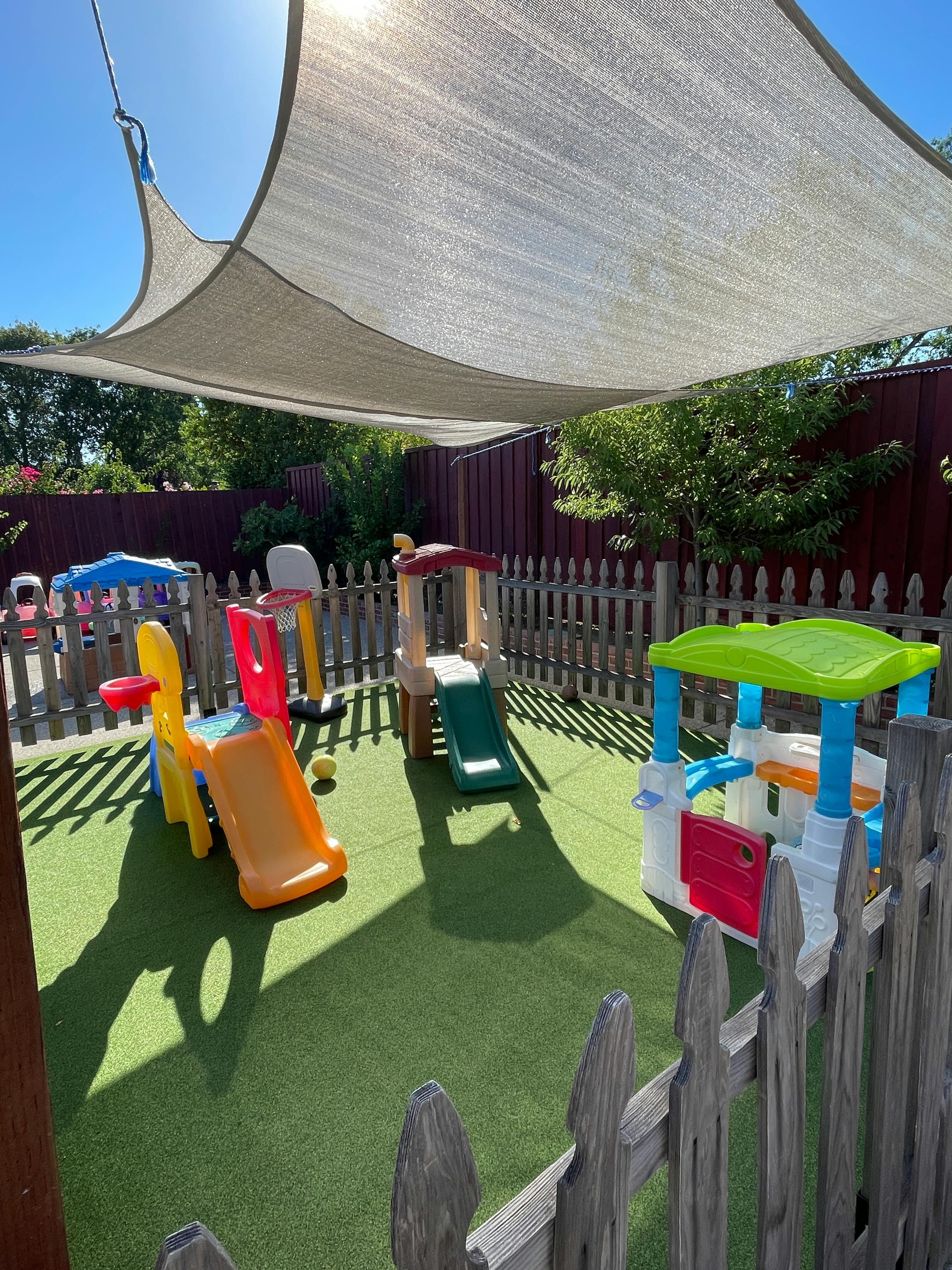 Playground with multiple slides and play structures under a shade sail