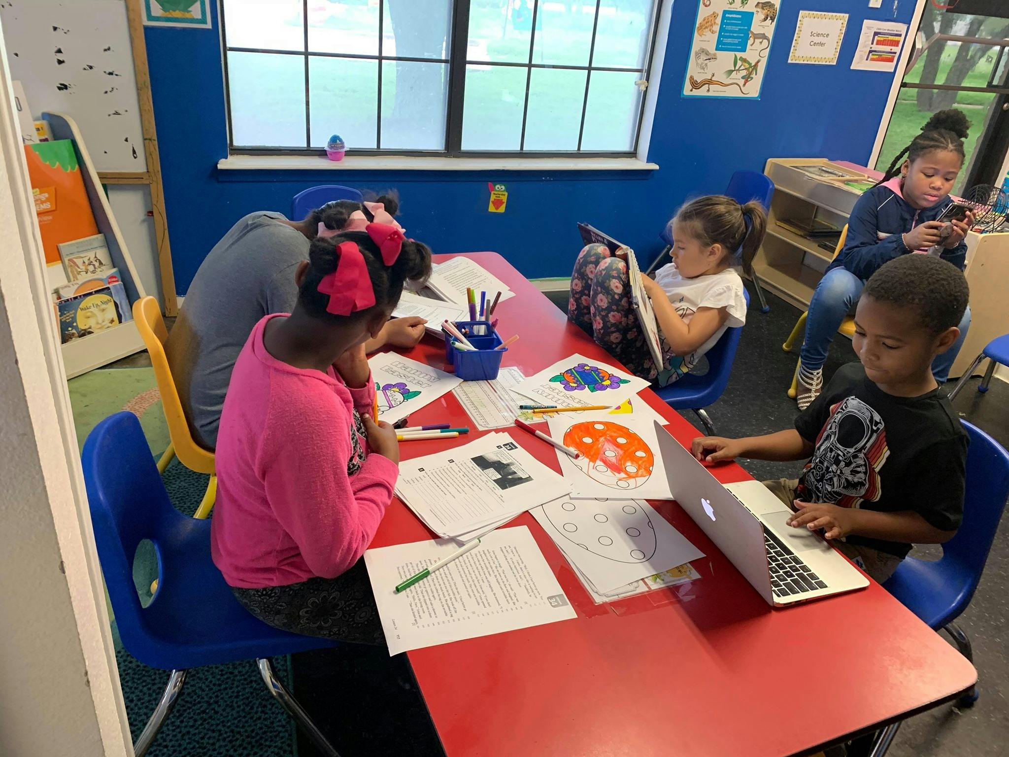 Children working at a red table in a classroom