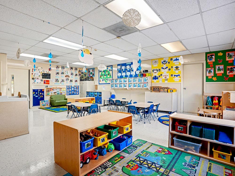 Colorful empty classroom with small tables and chairs, and decorations