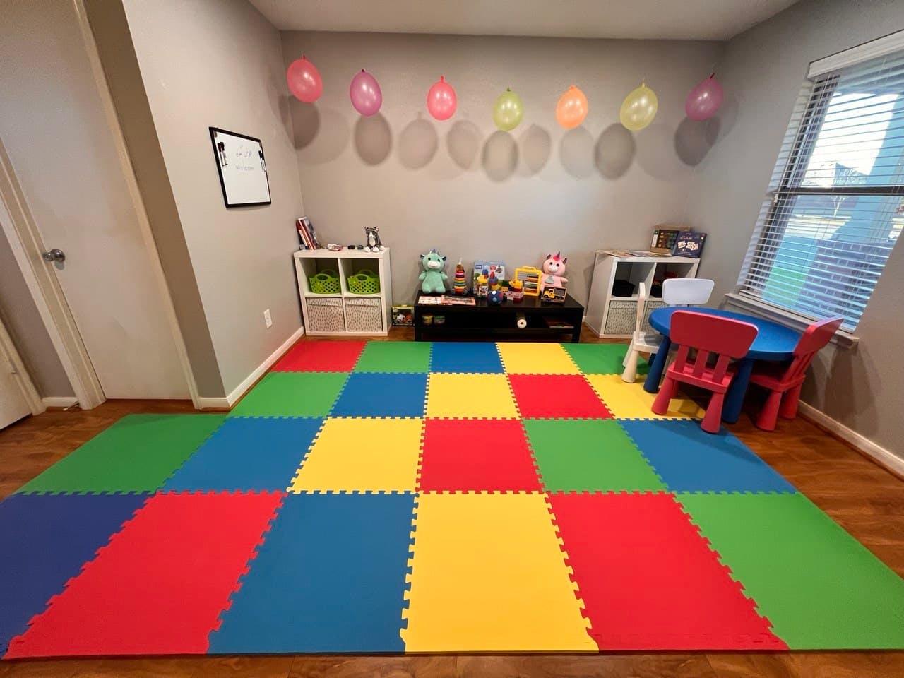 Playroom with colorful interlocking floor mats and balloons on the wall balloons
