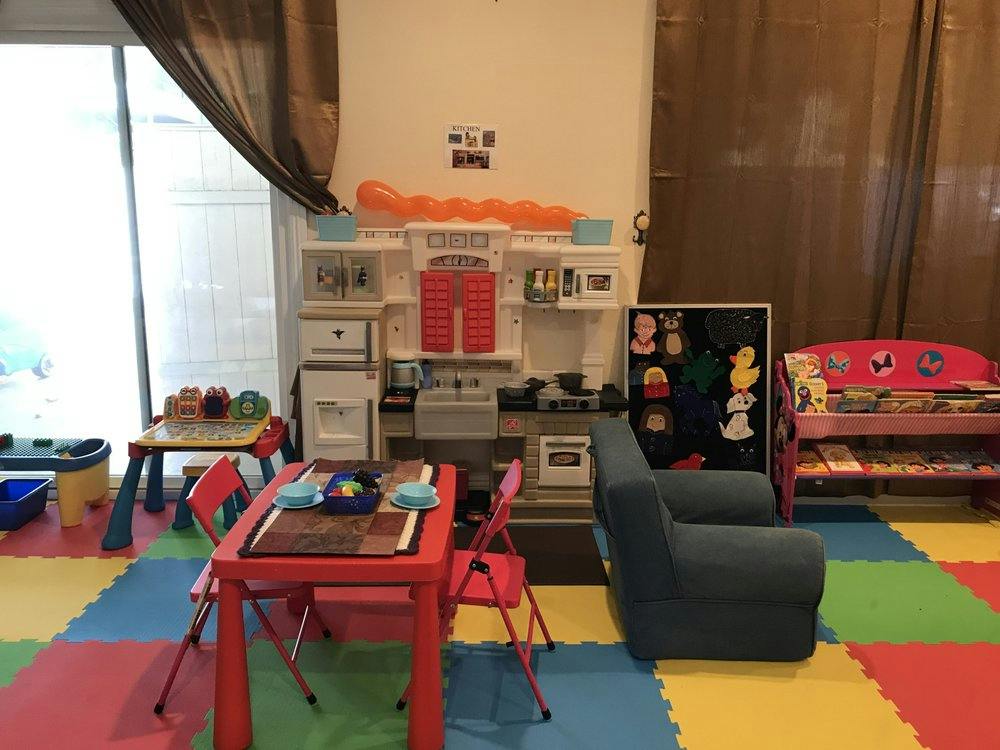 Playroom with colorful floor mats, small red table and chairs, and toy kitchen