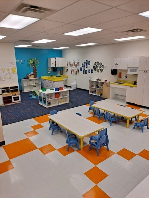 Classroom with small tables and chairs, blue and orange flooring