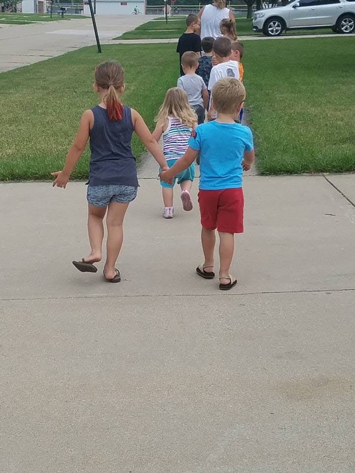 Children walking in a line on a sidewalk