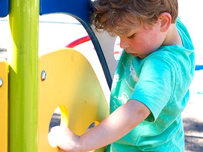 Child playing with a yellow panel on a playground structure
