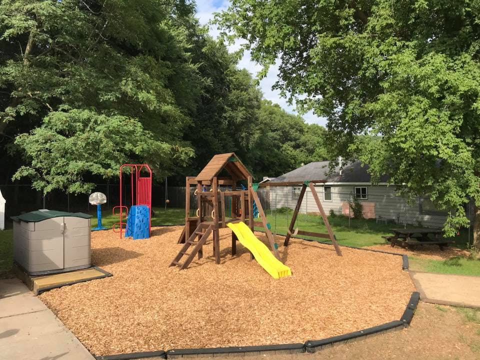 Outdoor playground with wooden play structure, yellow slide, and swings