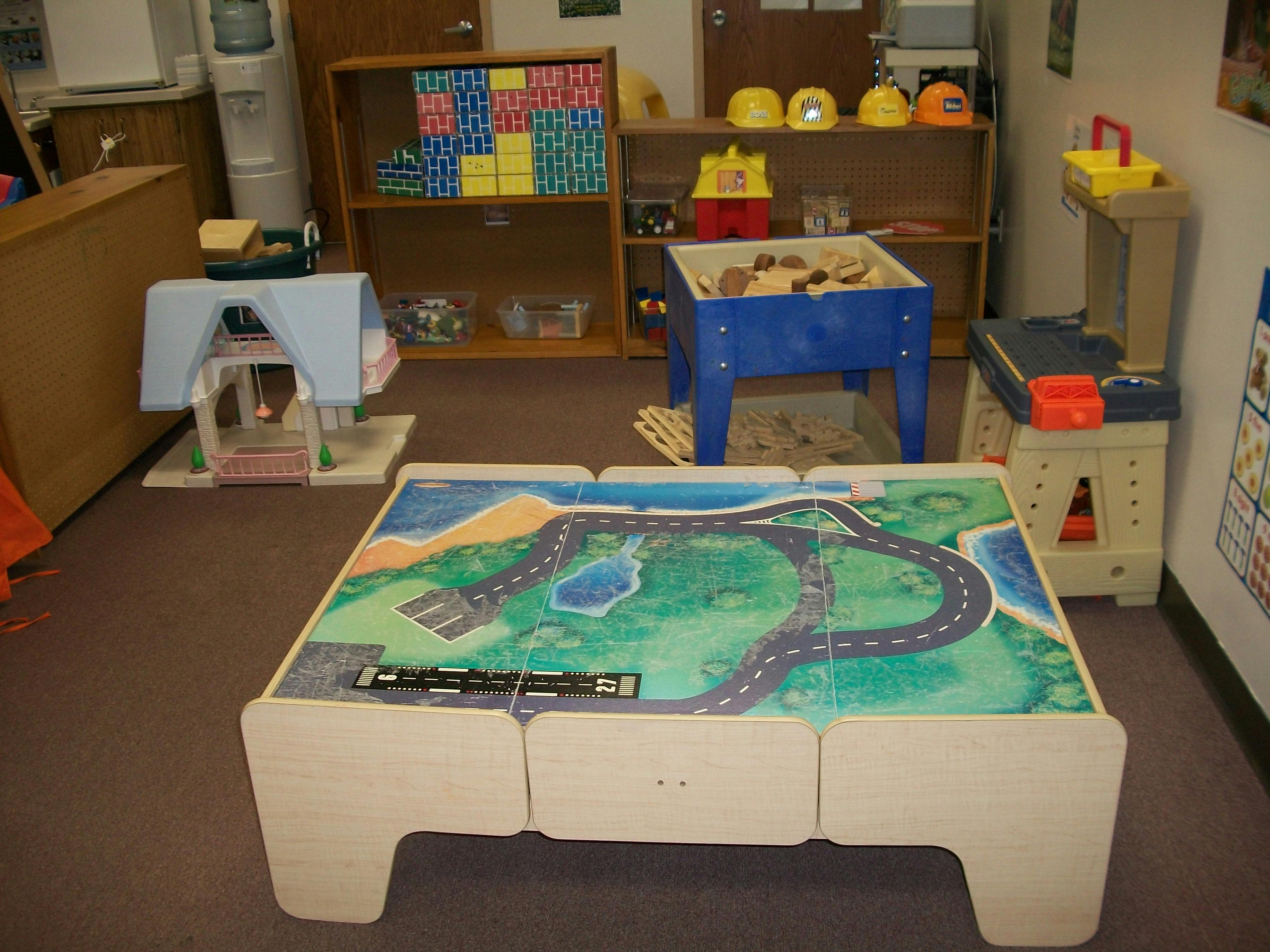 Playroom with a toy road map table, dollhouse, and toy construction hats