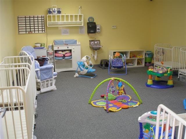 Nursery room with multiple cribs, play mats, and baby swings