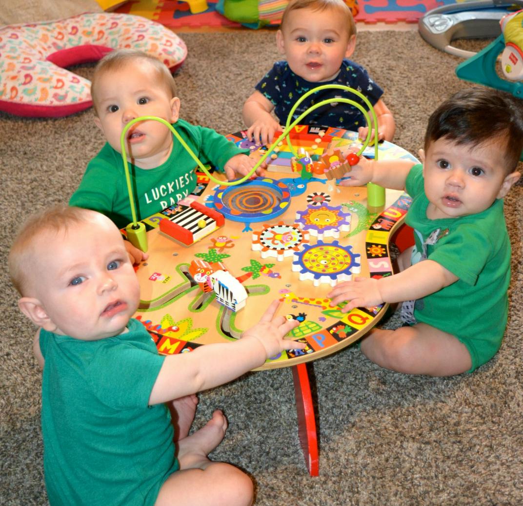 Four babies playing around a colorful activity table
