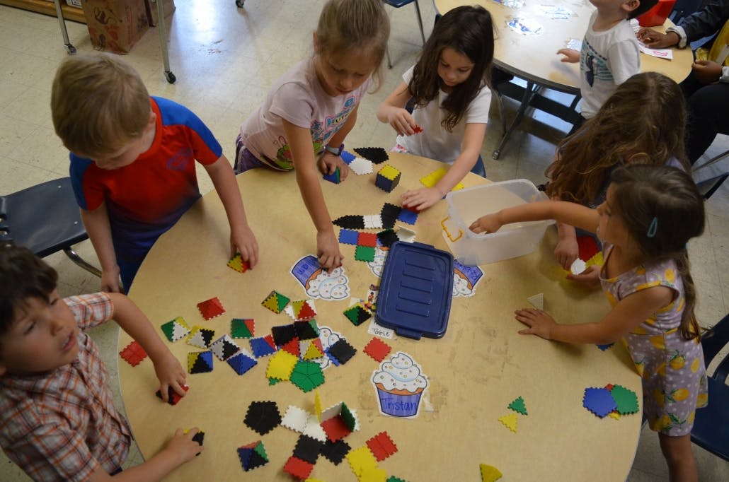 Children playing with colorful geometric shapes on a table