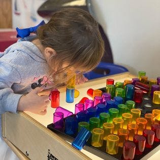 Child playing with colorful translucent blocks on a light table
