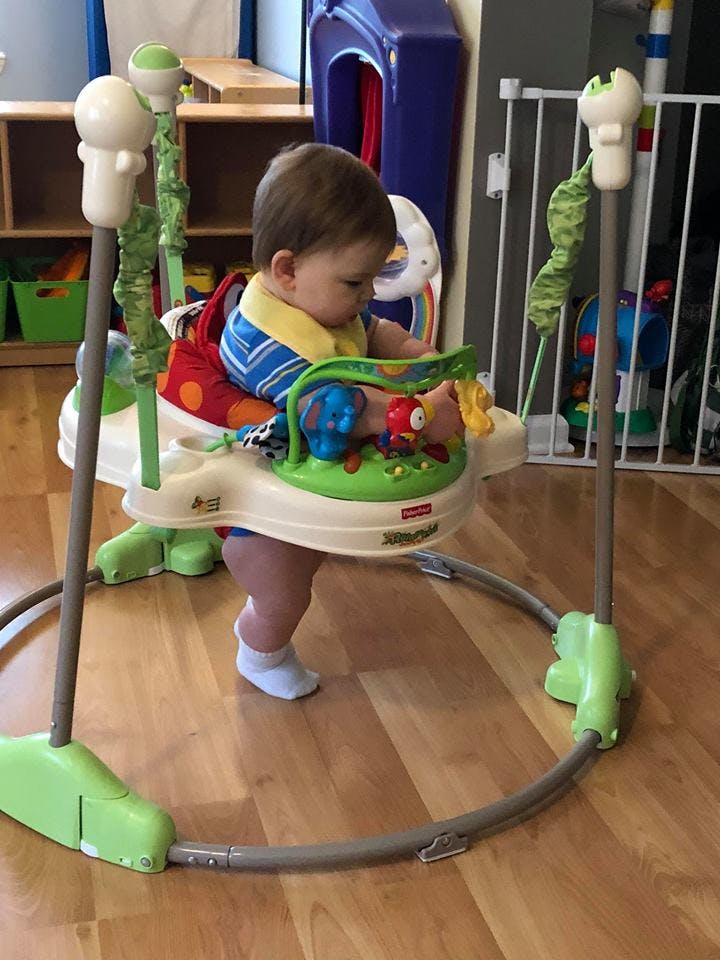 Child in a baby bouncer playing with toys