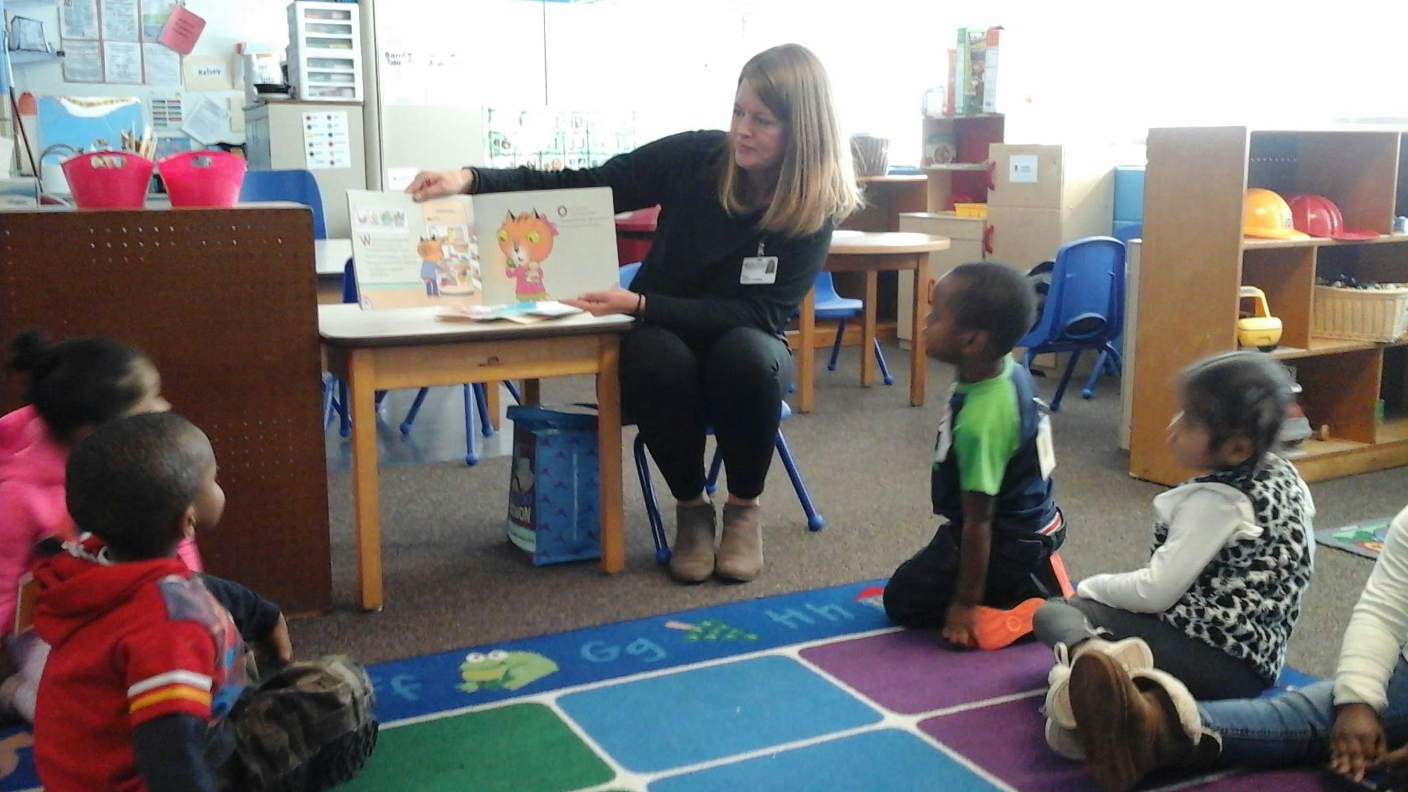 Person reading a book to children in a classroom