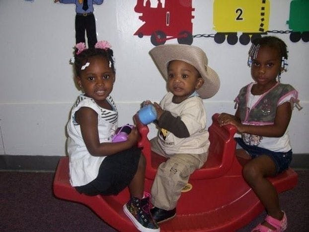 Three children sitting on a red seesaw