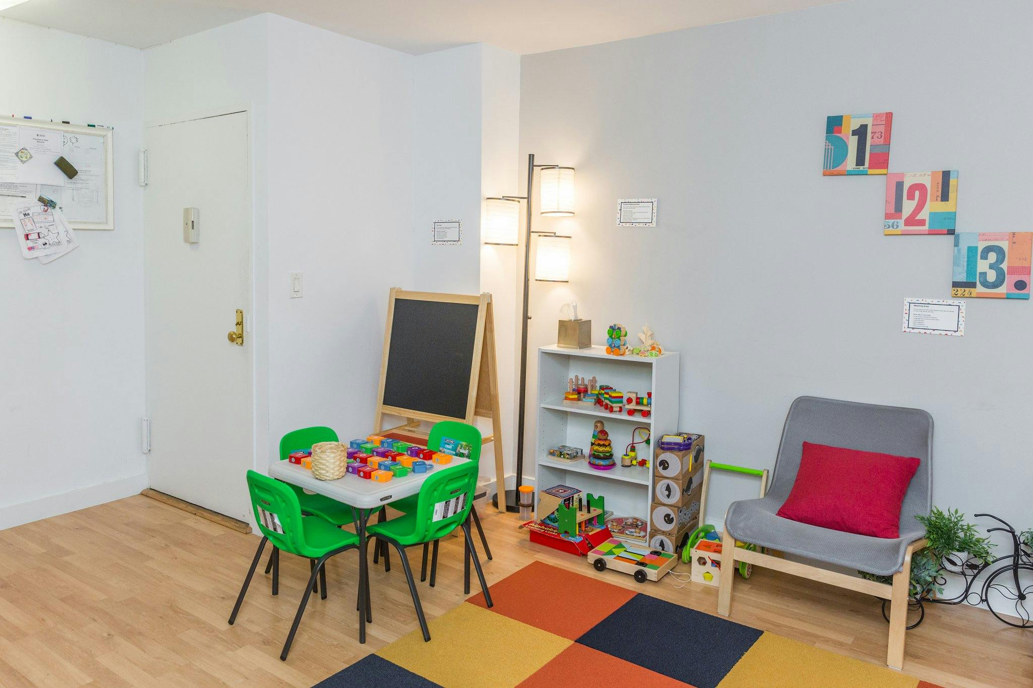 Playroom with small table and chairs, chalkboard, and shelves with toys