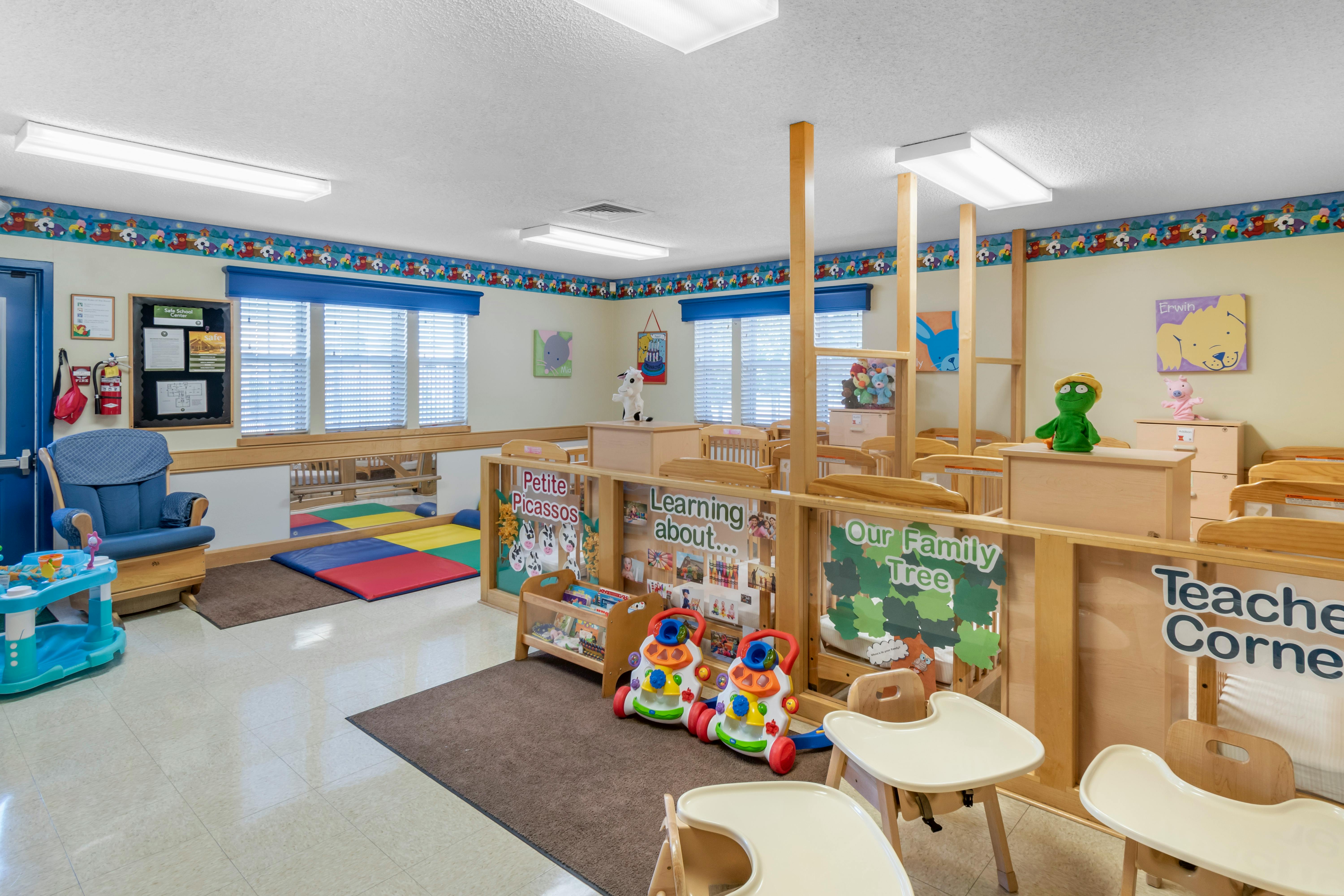 Classroom with cribs, playmats, a blue rocking chair, and various toys