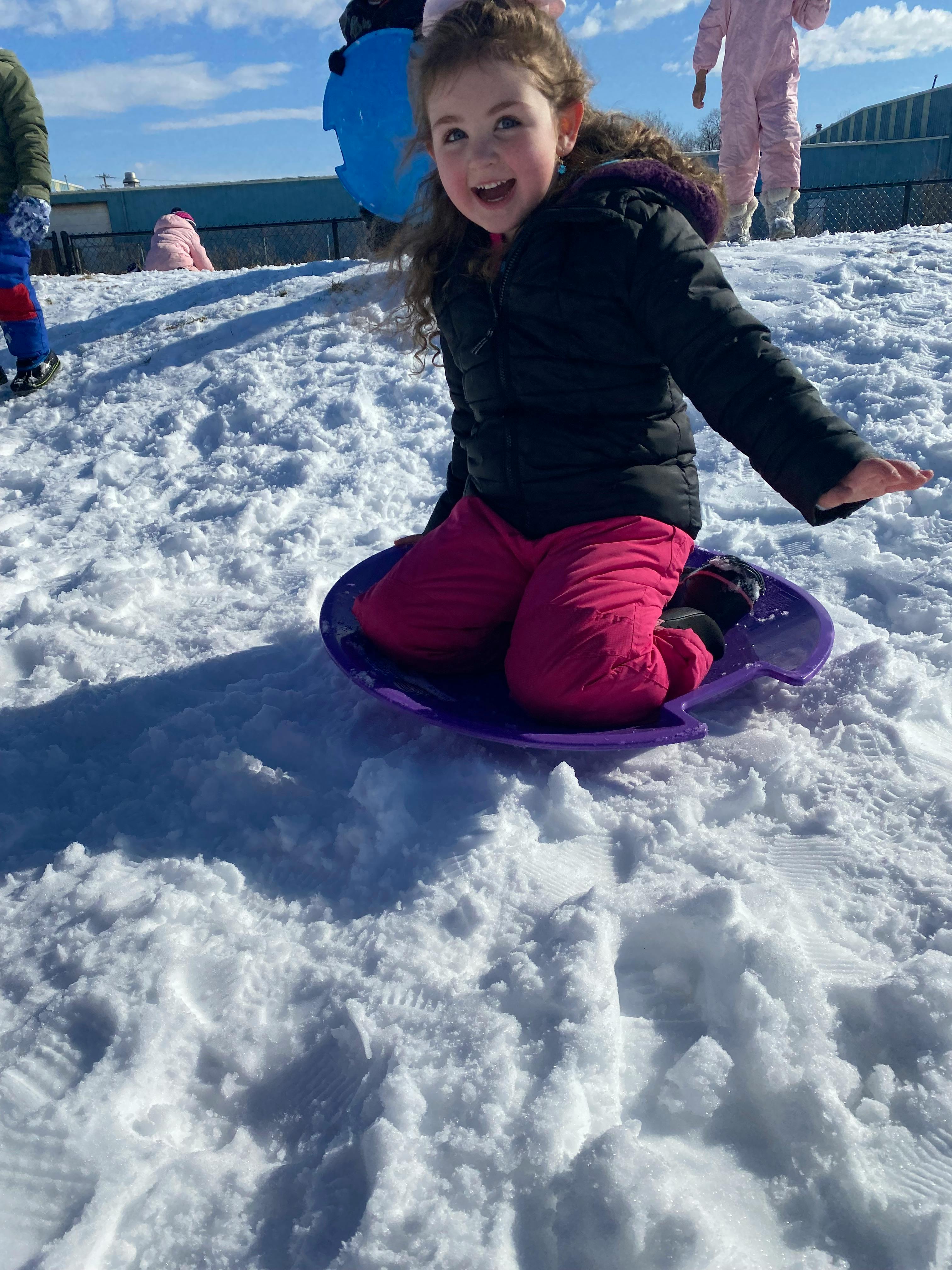 Child sitting on a purple sled in the snow