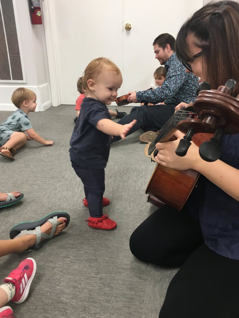 Person playing a string instrument for a child