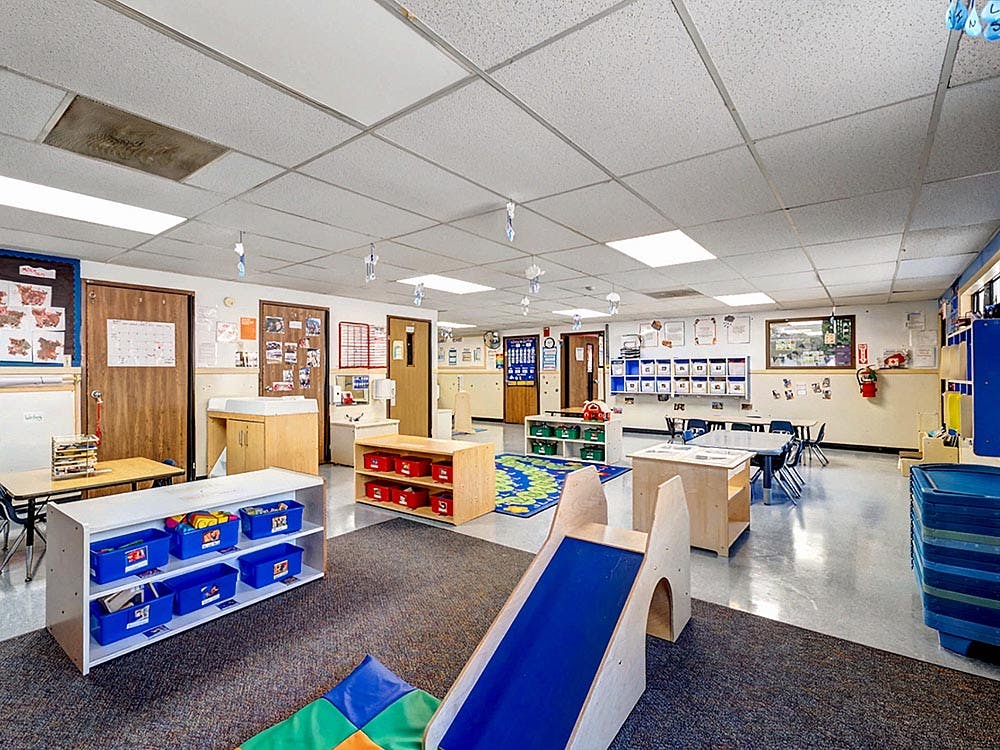 empty preschool classroom with play equipment and small tables