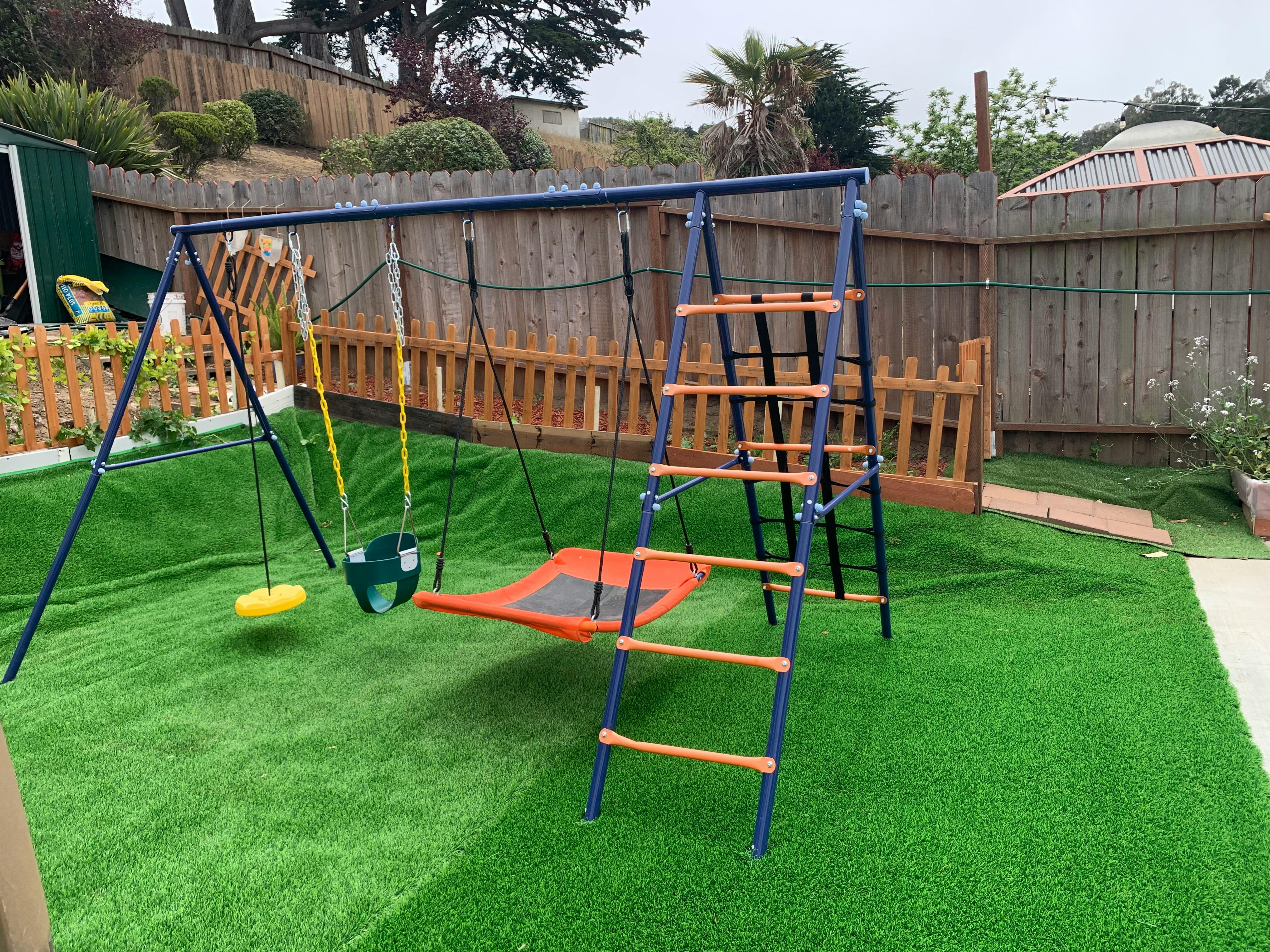 Swing set with a ladder and a flat swing on artificial grass
