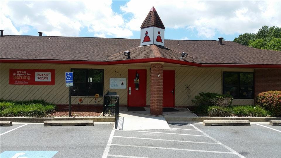child care center with a small tower feature, red doors, and a parking lot