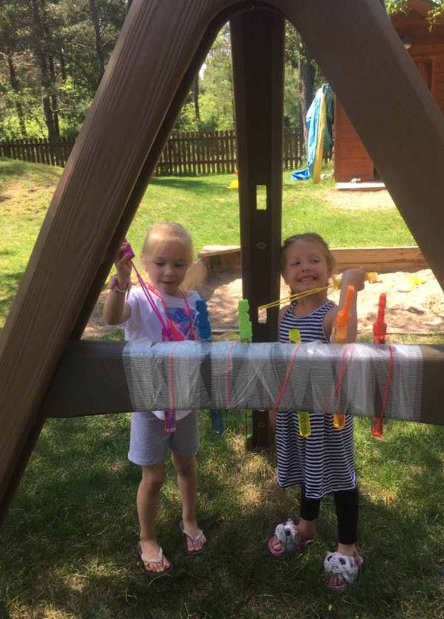 Two children playing with string and clothespins on a playground structure