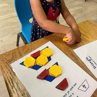 Child playing with geometric shape blocks on a paper activity