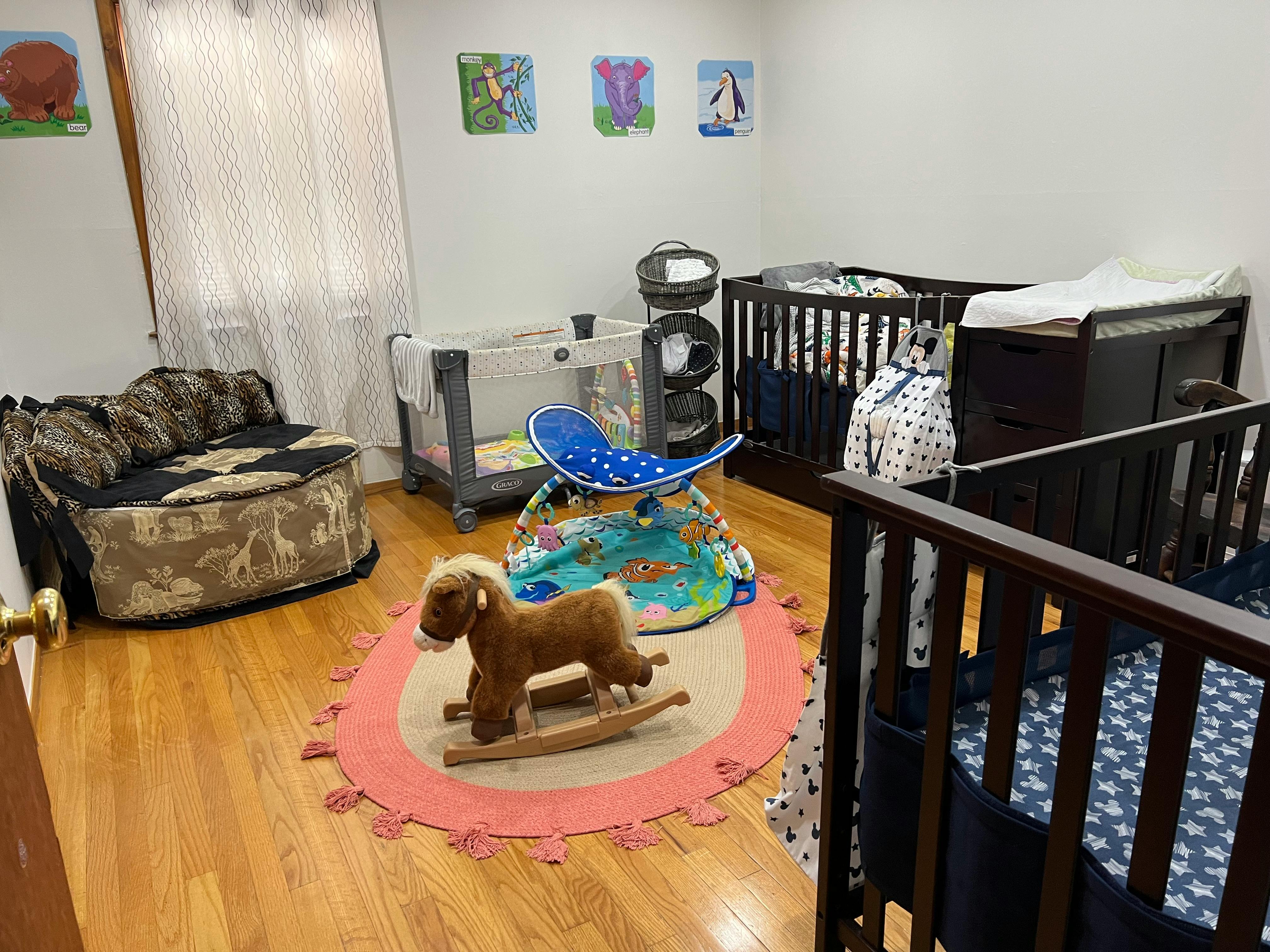 Nursery room with two cribs, a rocking horse, and a changing table