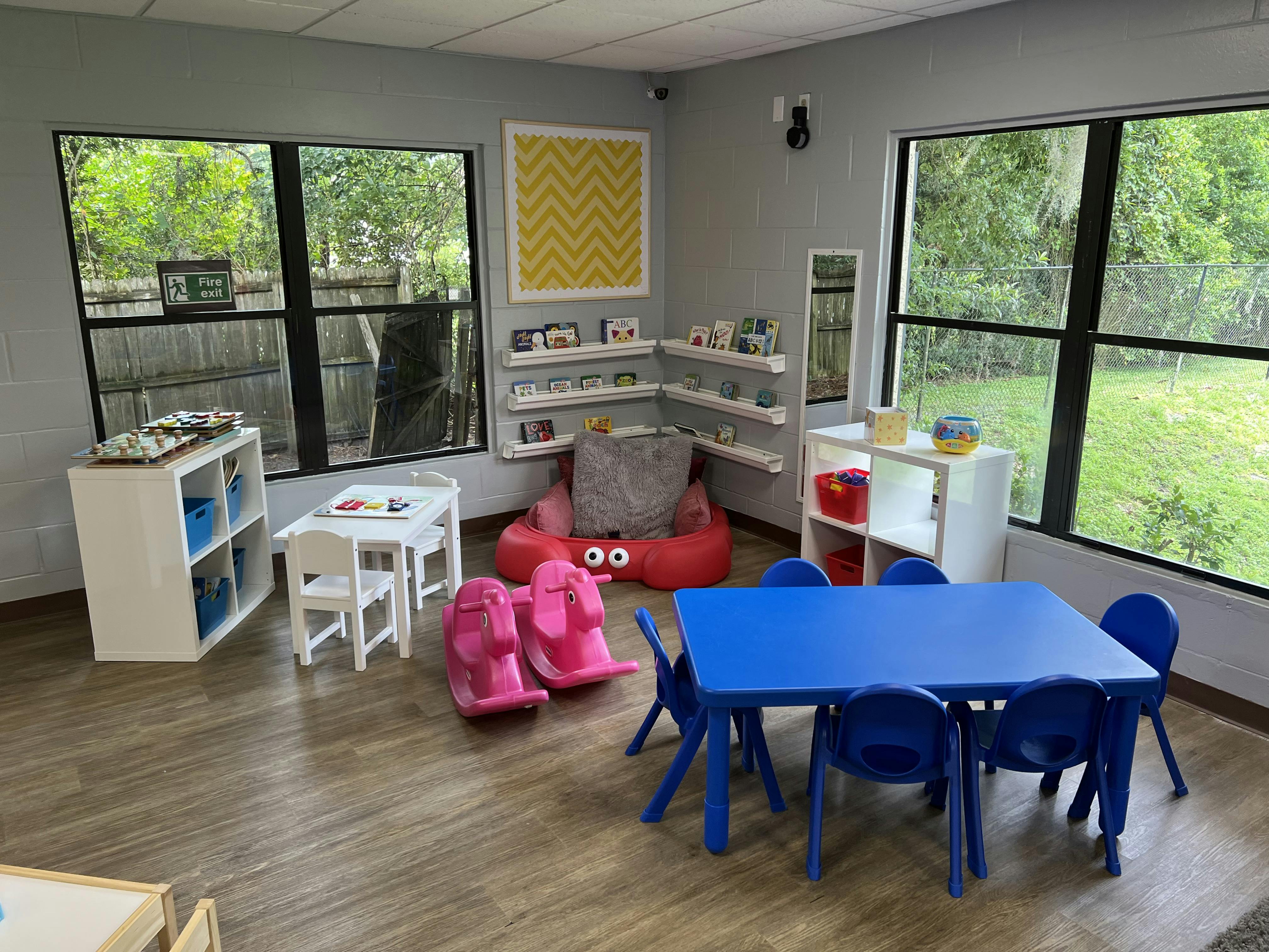 Children's classroom with small tables and chairs, and a reading nook