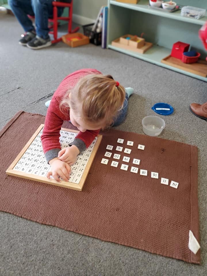 Child on floor working with number tiles on a mat