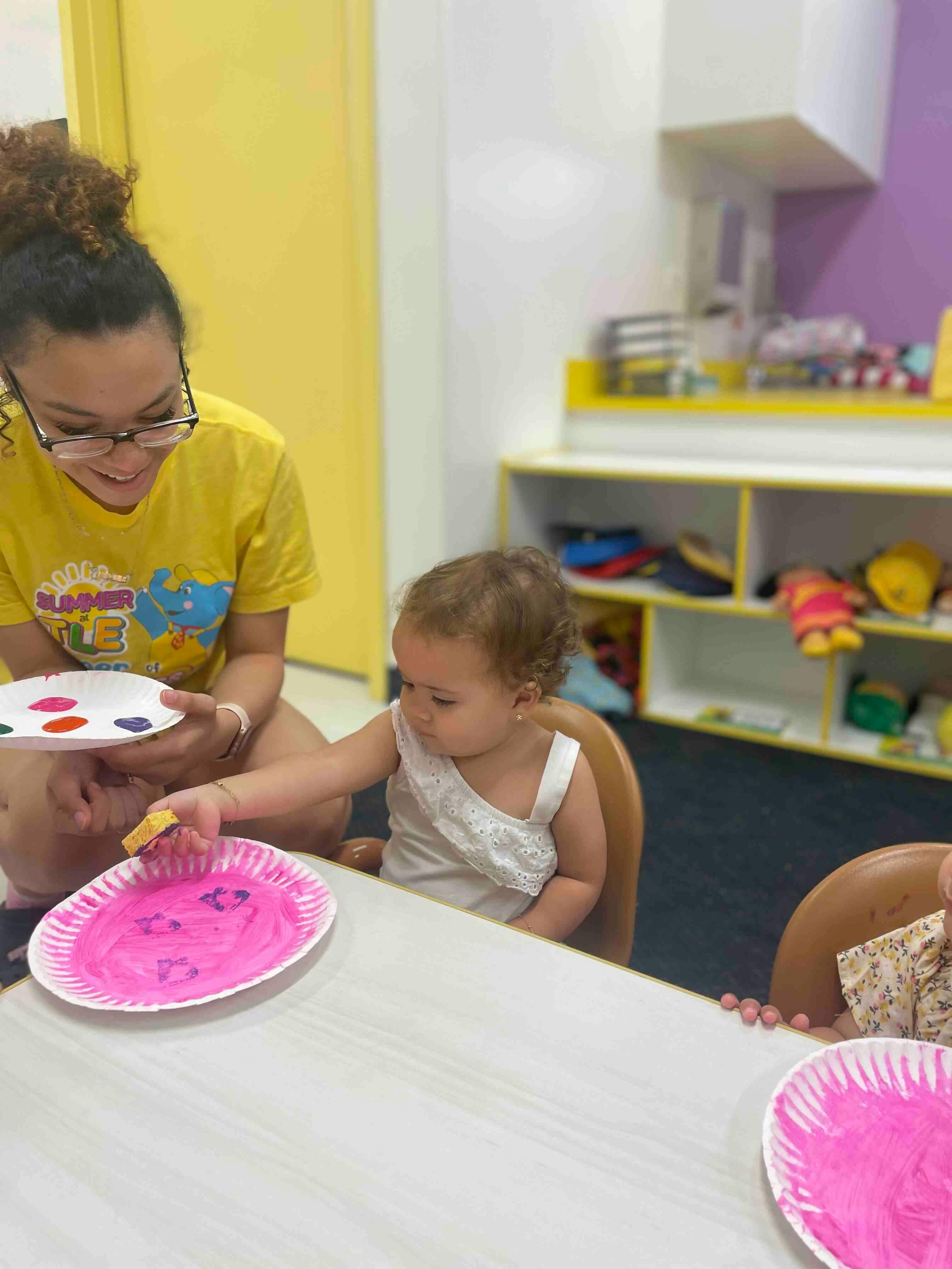 Person and child painting on paper plates